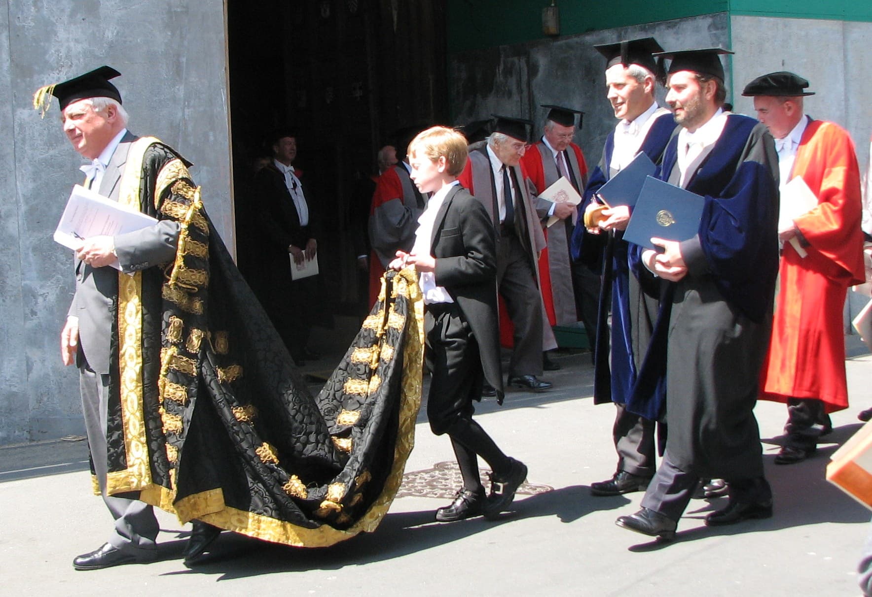 Oxford Proctors and members of Congregation in gowns, hoods and mortarboards processing out of the Sheldonian Theatre.