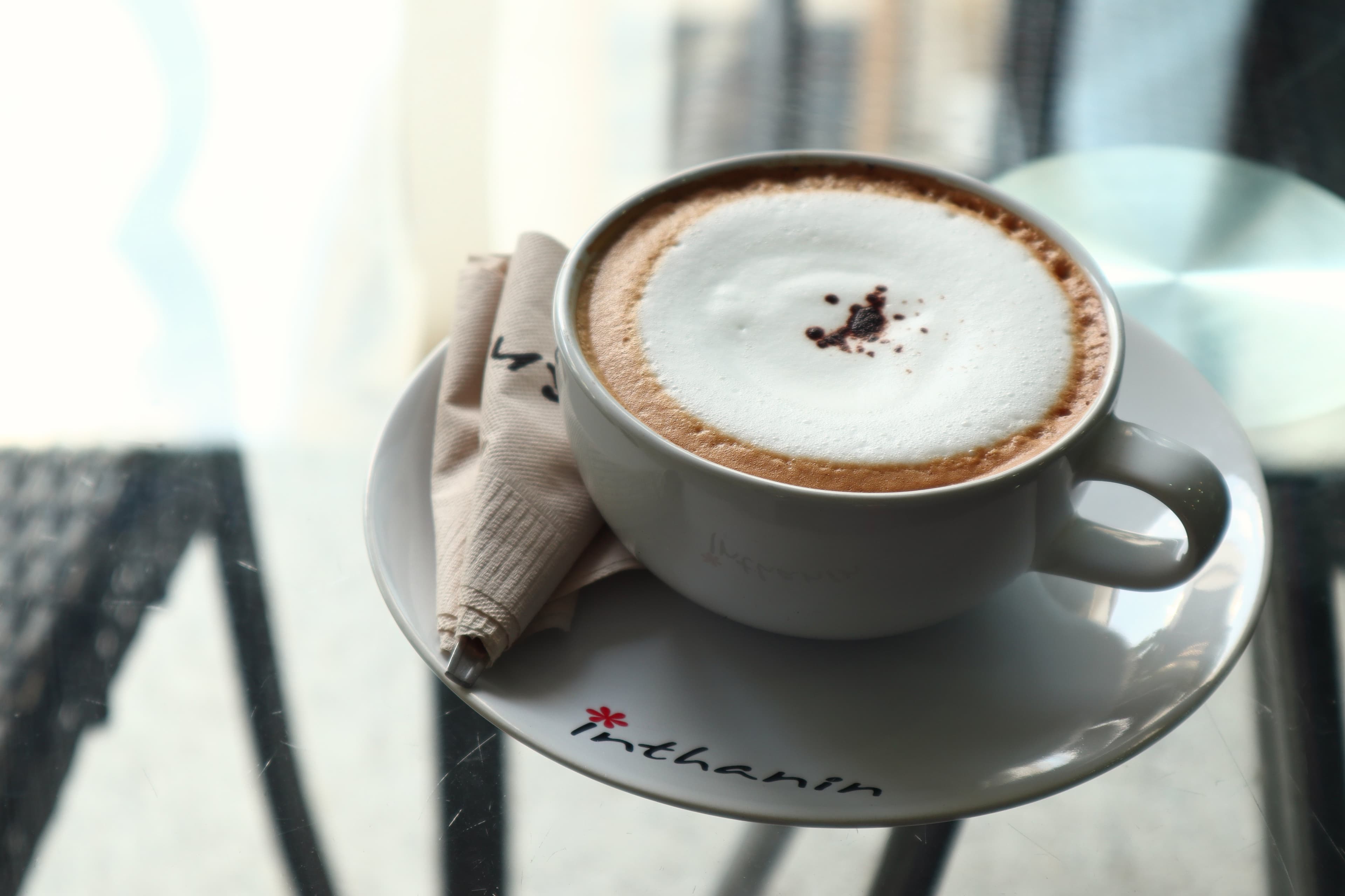 A cappuccino in a white cup, seen from above, with a pattern drawn in the milk foam.