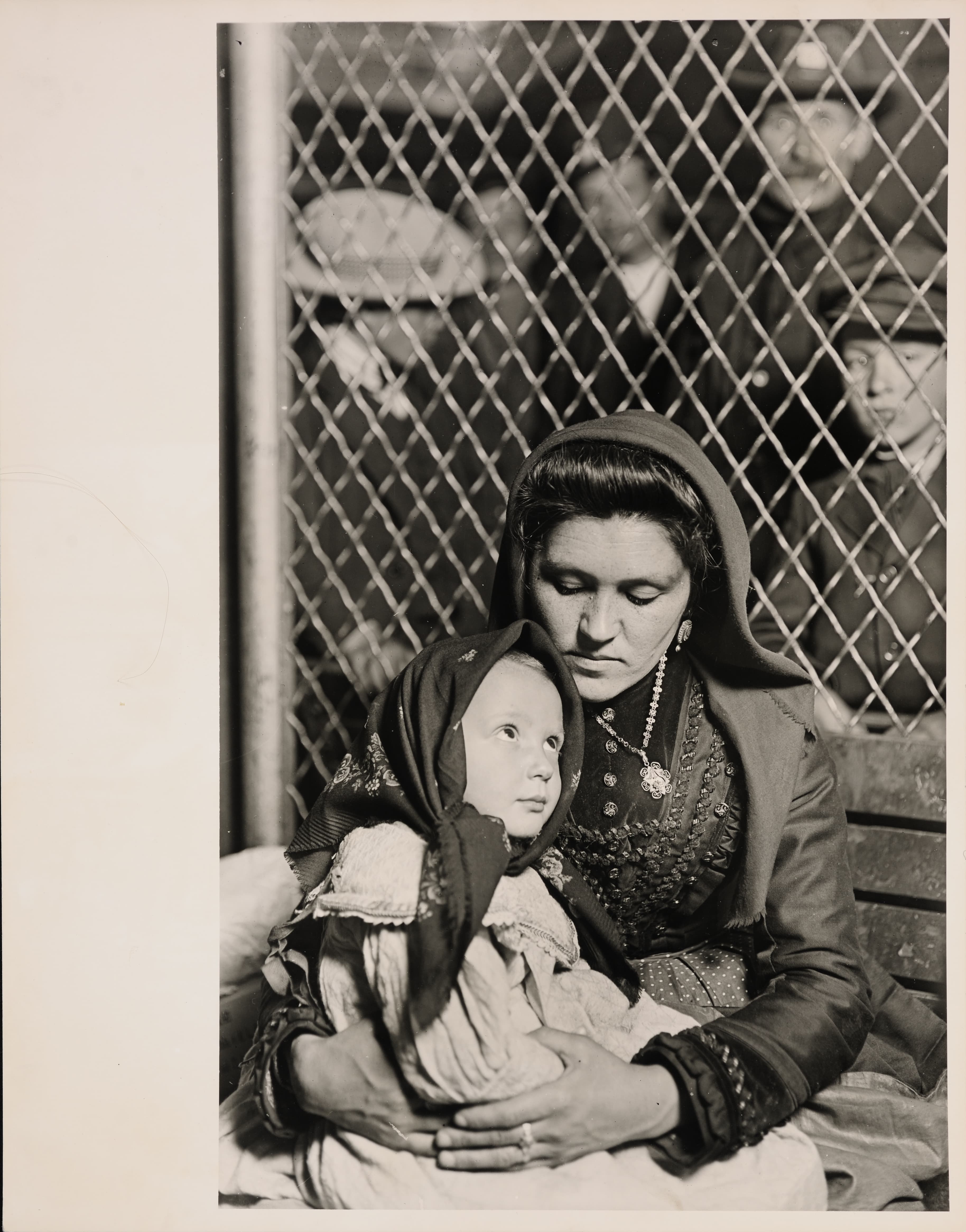 A 1905 black-and-white photograph of an Italian mother holding her child, newly arrived at Ellis Island.